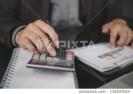 Accountant hand holding pen, use calculator, pointing financial data chart. Business finance concept. Man working office desk, analyze report, planning budget, corporate audit, check. 136895664