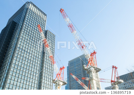 Tower cranes constructing buildings in the redevelopment of Tokyo's Marunouchi district, construction in progress in the high-rise building district Tower cranes constructing buildings in the redevelopment of Tokyo's Marunouchi district, construction in progress in the high-rise building district 136895719