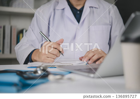 Doctor hand pen writing medical document on clipboard. Physician work office desk laptop stethoscope. Healthcare concept, write patient report, diagnosis, prescription, fill form, insurance, record. Doctor hand pen writing medical document on clipboard. Physician work office desk laptop stethoscope. Healthcare concept, write patient report, diagnosis, prescription, fill form, insurance, record. 136895727