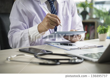 Doctor hand use digital tablet. Medical healthcare technology concept. Physician work office desk, check patient data, ehr emr record. Online consultation, telemedicine, modern clinic, stethoscope. Doctor hand use digital tablet. Medical healthcare technology concept. Physician work office desk, check patient data, ehr emr record. Online consultation, telemedicine, modern clinic, stethoscope. 136895737