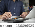 Businessman hand using calculator, laptop for financial analysis, tax calculation. Man working on accounting report, budget planning on office desk. Business finance and investment concept. 136896525