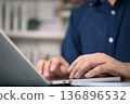 Close up of man hands typing on laptop keyboard at office desk. Businessman working on computer, sending email, programming. Business technology, remote work, and online communication concept. 136896532