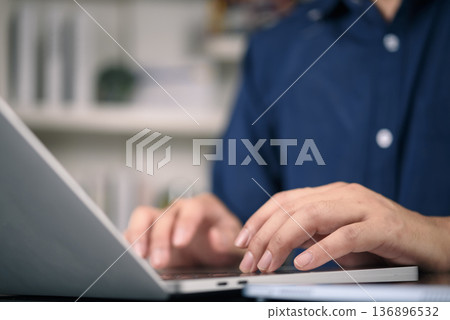 Close up of man hands typing on laptop keyboard at office desk. Businessman working on computer, sending email, programming. Business technology, remote work, and online communication concept. Close up of man hands typing on laptop keyboard at office desk. Businessman working on computer, sending email, programming. Business technology, remote work, and online communication concept. 136896532