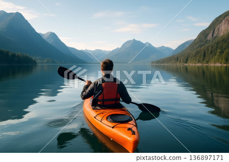 Adventurous kayaker paddling towards majestic mountains on a serene lake at sunrise, enjoying the tranquility of nature 136897171