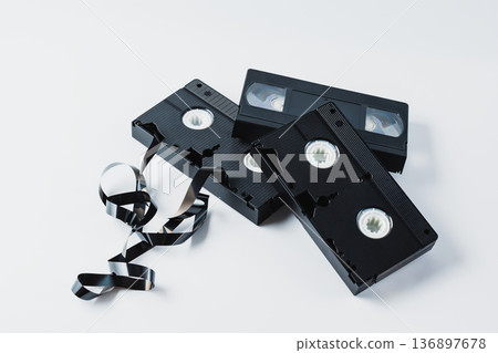 Old video tapes from the 90s on a white insulated background, with visible crumpled tape Old video tapes from the 90s on a white insulated background, with visible crumpled tape 136897678