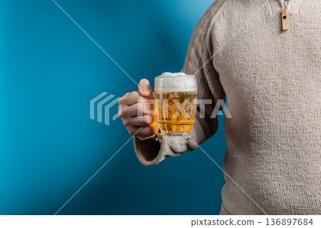 A man holding a filled glass of light beer 136897684