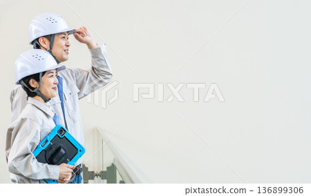 Male and female engineers standing indoors in a building with a tablet PC 136899306