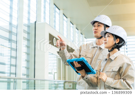 男性工程師和女工程師一邊查看平板電腦，一邊檢查建築物內部 136899309