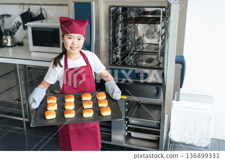 Girl baking cookies in the kitchen using the oven 136899331