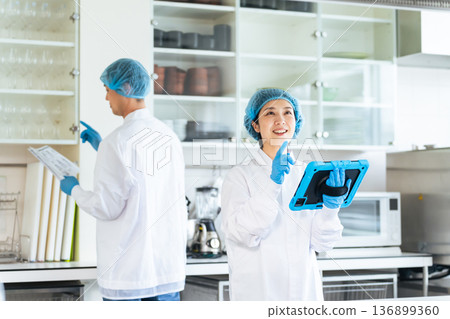 身穿衛生白大褂的男女工作人員正在檢查廚房 136899360