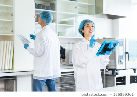 Male and female workers in sanitary white coats checking the kitchen 136899361