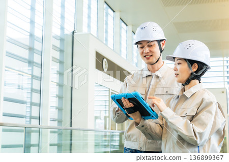 Male and female engineers inspecting the interior of a building while looking at a tablet PC Male and female engineers inspecting the interior of a building while looking at a tablet PC 136899367