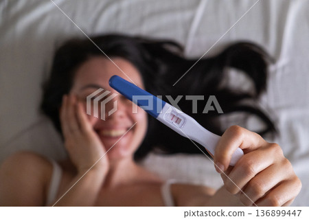 Surprised Woman with Positive Pregnancy Test Surprised Woman with Positive Pregnancy Test 136899447
