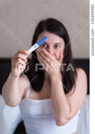 Surprised Woman with Positive Pregnancy Test Surprised Woman with Positive Pregnancy Test 136899460