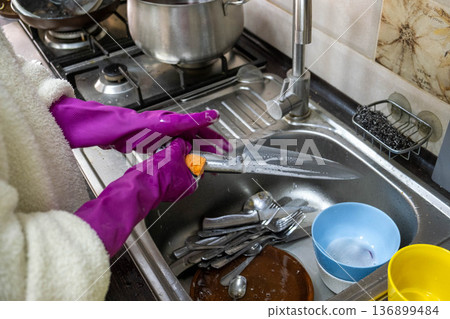 Washing dishes in kitchen sink with purple rubber gloves Washing dishes in kitchen sink with purple rubber gloves 136899484