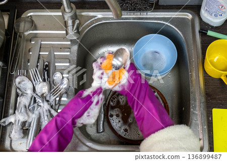 Washing dishes in kitchen sink with purple rubber gloves Washing dishes in kitchen sink with purple rubber gloves 136899487
