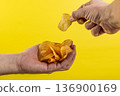 Potato chips in hand on yellow background 136900169