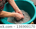 Grandma washes clothes in a poor neighborhood.Hand washing of household clothes 136900170