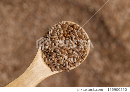 flax seeds in a spoon, a simple wooden spoon filled with fresh flax seeds 136900230
