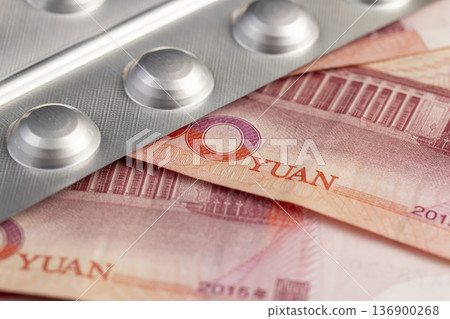 Chinese cash for one hundred yuan and pills in a packaged blister, medicines and red Chinese cash together 136900268