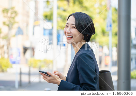 A businesswoman operating a smartphone in an office district A businesswoman operating a smartphone in an office district 136900306