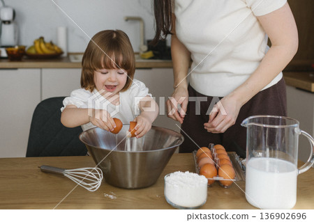 Mother and little daughter baking together in modern kitchen at home, happy family cooking and spending time together 136902696
