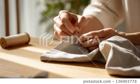 在溫暖的陽光下，一位婦女的雙手正在縫紉 136903778