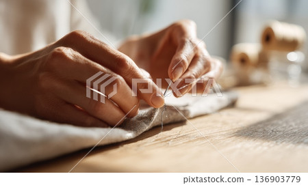 在溫暖的陽光下,一位婦女的雙手正在縫紉 在溫暖的陽光下,一位婦女的雙手正在縫紉 136903779