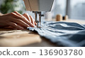 Woman's hands operating a sewing machine 136903780