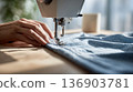 Woman's hands operating a sewing machine 136903781