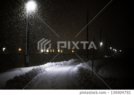 Snowstorm night road and house lights: ruts lit by streetlights and the winter way home 136904792