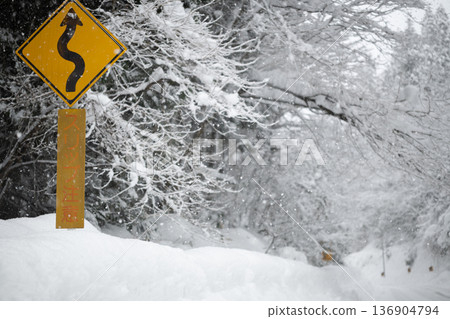 Snowy winter mountain roads and road signs warning of slippery conditions: winter traffic safety and danger warnings Snowy winter mountain roads and road signs warning of slippery conditions: winter traffic safety and danger warnings 136904794