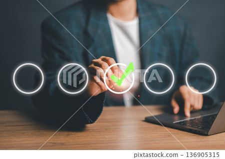 Professional businessman using a virtual interface to select an option with a green checkmark, symbolizing success and decision-making. Professional businessman using a virtual interface to select an option with a green checkmark, symbolizing success and decision-making. 136905315