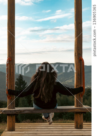 Woman Sitting on a Swing Over Mountain Valley Woman Sitting on a Swing Over Mountain Valley 136905365