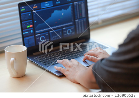Hands working on a laptop displaying financial data Hands working on a laptop displaying financial data 136906522