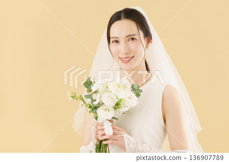 Portrait of a young bride in a wedding dress against a beige background 136907789