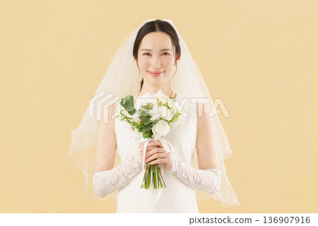 Portrait of a young bride in a wedding dress against a beige background 136907916