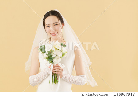 一位身穿婚紗的年輕新娘的肖像，背景是米色。 136907918