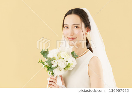 Portrait of a young bride in a wedding dress against a beige background 136907923