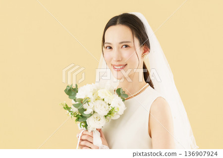 Portrait of a young bride in a wedding dress against a beige background Portrait of a young bride in a wedding dress against a beige background 136907924