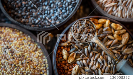 Array of bowls filled with various types of whole grains, with a focus on a spoonful of seeds. 136908252