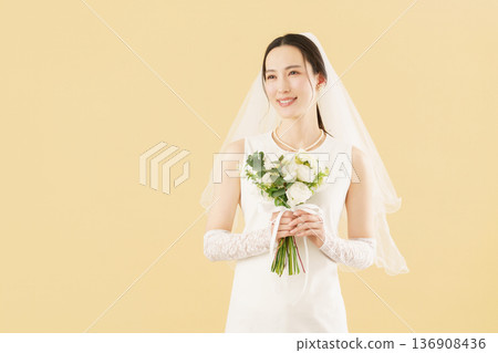 Portrait of a young bride in a wedding dress against a beige background 136908436