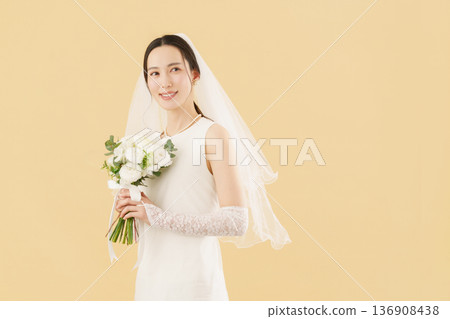 一位身穿婚紗的年輕新娘的肖像，背景是米色。 136908438