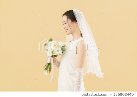 Portrait of a young bride in a wedding dress against a beige background 136908440