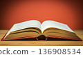 Inviting open book lies on a wooden table with a warm orange background, symbolizing knowledge and learning. 136908534