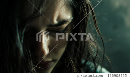 Contemplative woman in a close-up shot, with a moody and introspective ambiance highlighted by dramatic lighting. 136908535