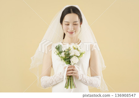 Portrait of a young bride in a wedding dress against a beige background 136908547