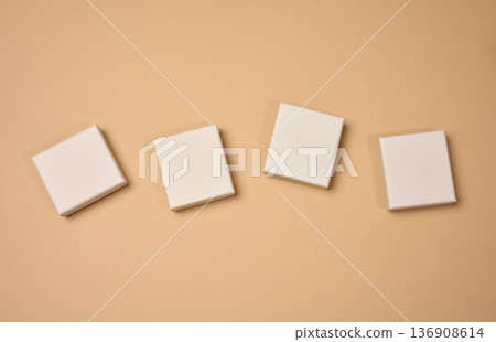Four beige square cardboard boxes on a beige background. Four beige square cardboard boxes on a beige background. 136908614