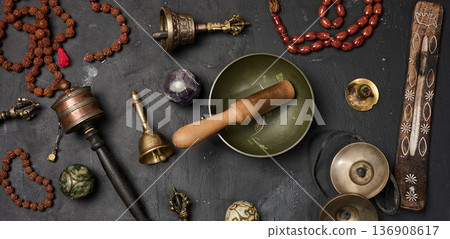 Tibetan singing bowl, wooden resonator, ritual vajras, bell, prayer wheel, rosary beads, and incense on a black background Tibetan singing bowl, wooden resonator, ritual vajras, bell, prayer wheel, rosary beads, and incense on a black background 136908617