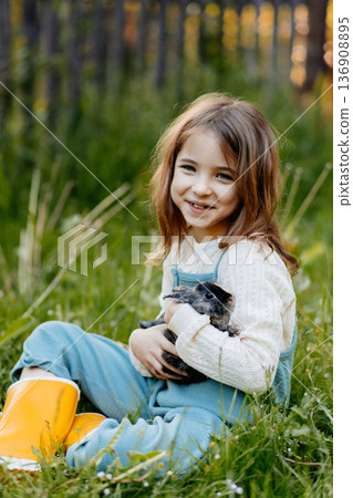Young girl gently cuddles a fluffy bunny in her arms. Young girl gently cuddles a fluffy bunny in her arms. 136908895